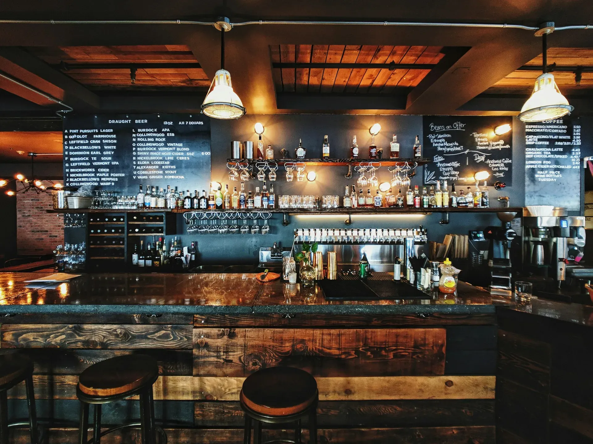 Gemütliche Bar mit Tafelwand, Flaschenregal und warmem Licht