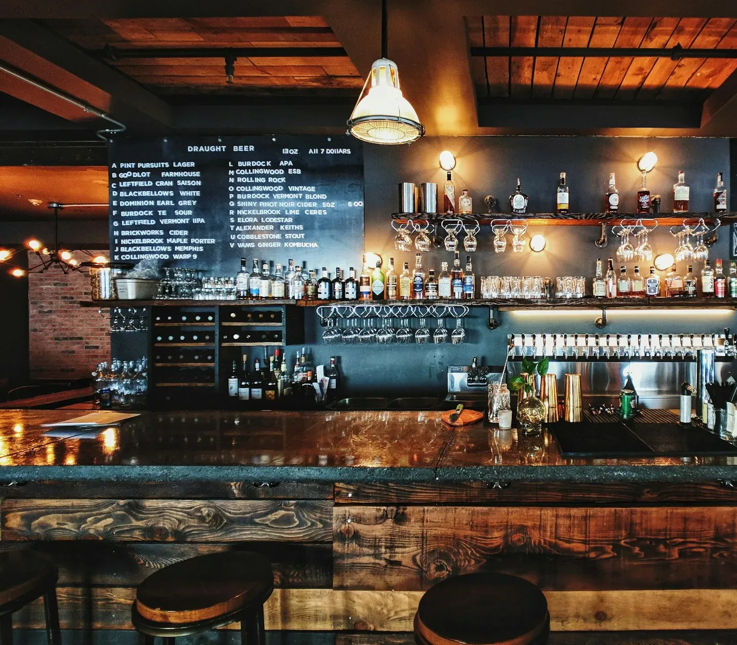 Bartresen mit Hockern, Kreidetafel und Pendelleuchten im Abendlicht